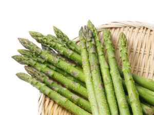 新鮮な緑のアスパラガスが上品なライフスタイルマガジン風のスタイルで、白い背景に描かれています。